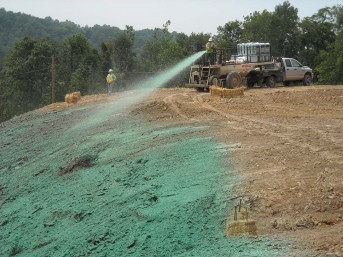 Truck spraying green hydromulch on a graded slope